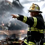 Anggota bomba mengarahkan pancutan air, menunjukkan pam air khas untuk pemadaman kebakaran.