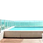 A pool on the roof of a building where clean water is reflected into sky blue by the bright daylight, depicting this water pump is built to run for swimming.